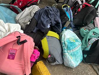 Colorful assortment of backpacks on the blacktop of a schoolyard
