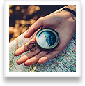 A hand is shown holding a compass against a topographical map