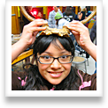 A young girl playfully wears a pair of antlers on her head